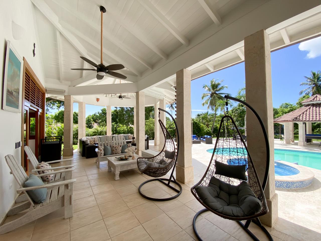 Hanging chairs on the covered terrace beside the pool at Cajuiles 41 Estate