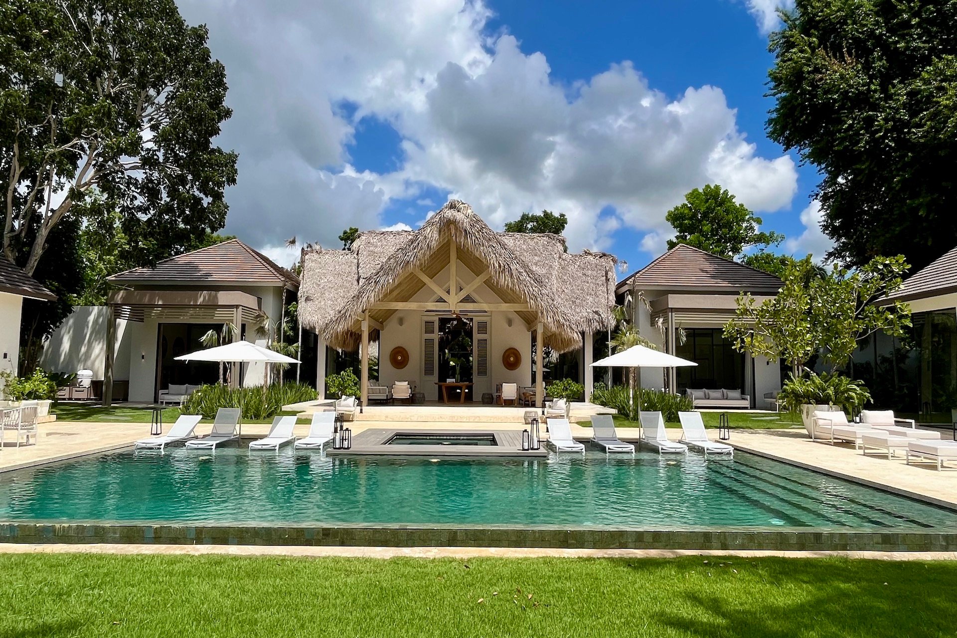 Front view of the infinity pool, jacuzzi deck and thatched pool pavilion set between the villa's two wings, Punta Águila Golf Villa, Casa de Campo