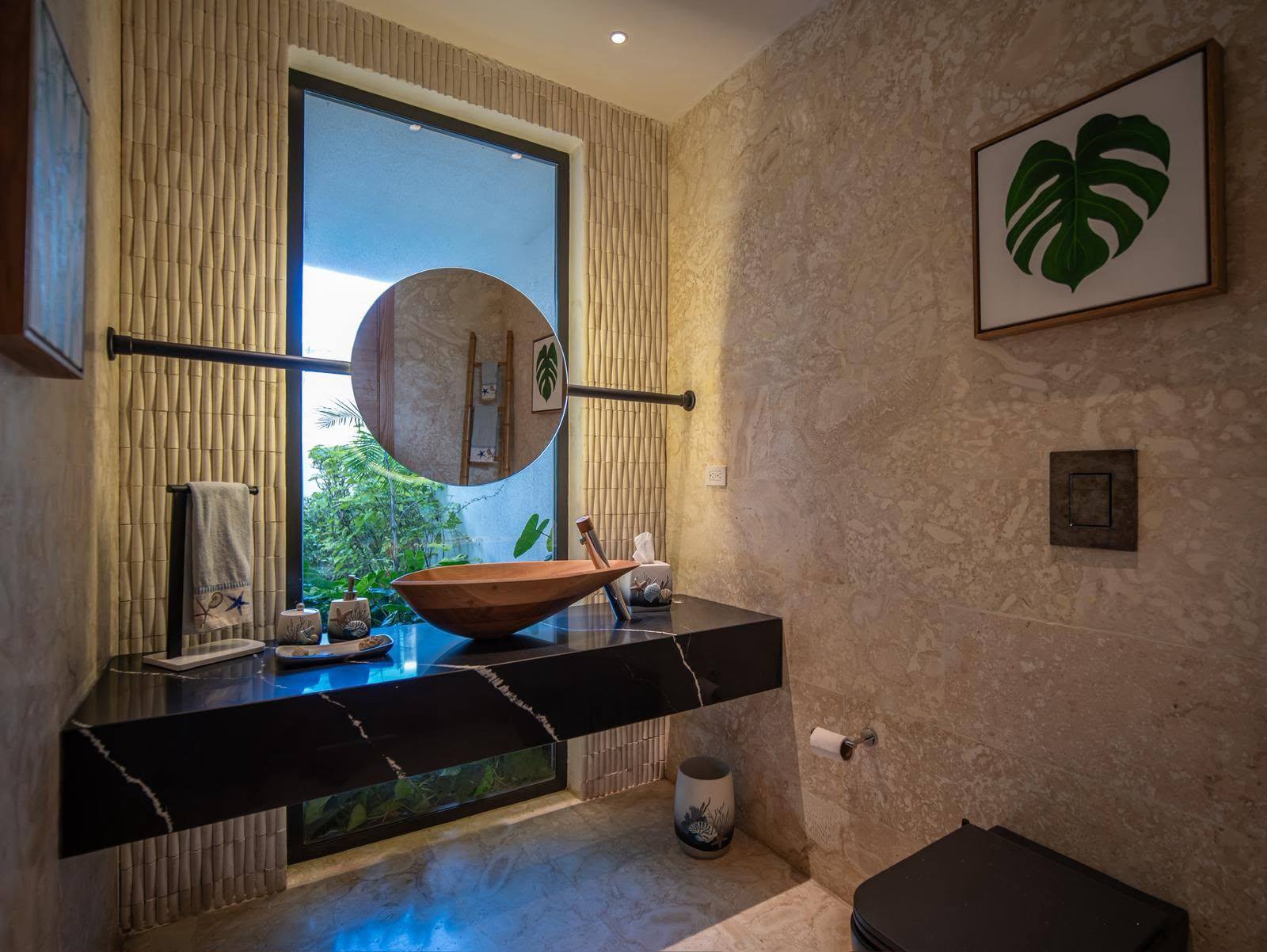 Stone bathroom with sculpted wooden basin and a window onto the water garden